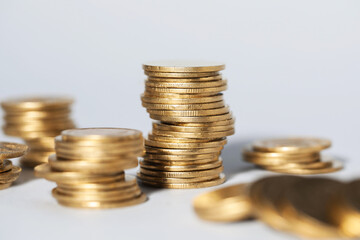 Many stacked coins on light grey background, closeup