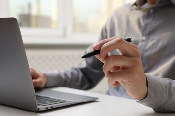 Electronic signature. Man with stylus and laptop at white table indoors, closeup