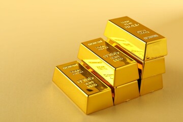 Shiny gold bars on beige background, closeup. Space for text