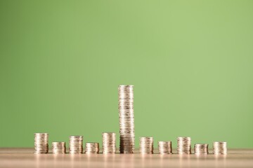 Stacks of coins on table against green background