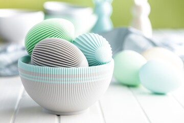 Easter decoration. Colorful eggs in bowl on white table.
