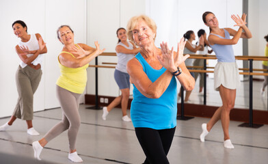 Fototapeta premium Dancing active women engaged in a group class practice energetic dance in a modern dance studio