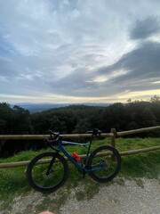 Blue road bike parked at a wooden fence in a beautiful cloudscape landscape in the forest mountain in Girona, Catalonia