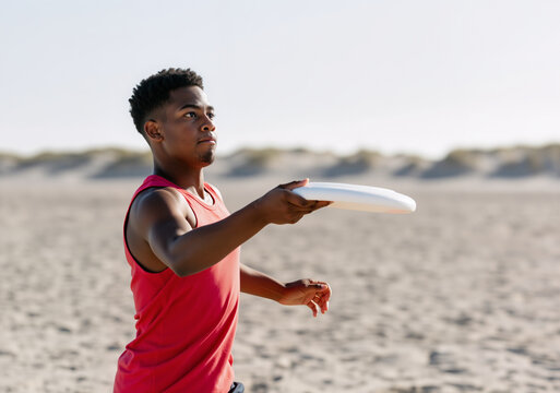 Concentrated sportsman throwing flying disc on beach