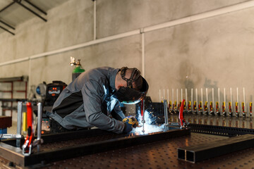 Professional welder wearing protective gear skillfully joining metal components on a welding table, creating sparks and showcasing expertise in metal fabrication