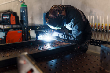 Professional welder wearing protective gear and using a welding torch to join metal parts, creating...