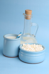 bottle with milk and cottage cheese on a blue background
