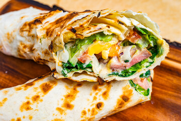 Tasty vegetable and cheese wrap on a wooden plate