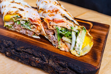 Savory grilled wraps filled with fresh ingredients on wooden board