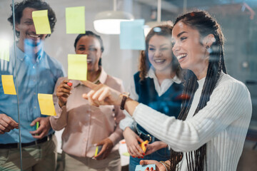 Business team brainstorming and planning with sticky notes on glass wall in office
