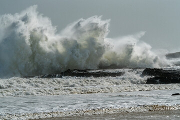 A wave breaks over a reef  as a storm approaches