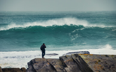 Photographer taking a picture of a large incoming wave