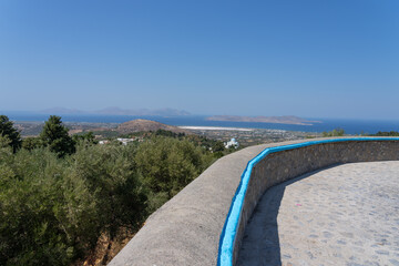 View from platform in hills of the island of Kos overlooking olive orchard and trees with church to Aegean and other Dodecanese Islands.