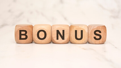 wooden blocks spelling BONUS on a marble surface, symbolizing rewards and extra benefits