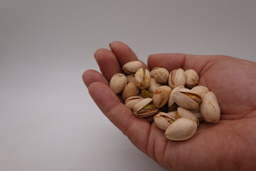 Hand holding pistachios on white background