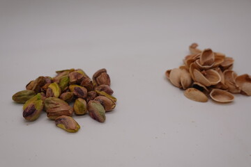 Shelled pistachios and empty shells on white background