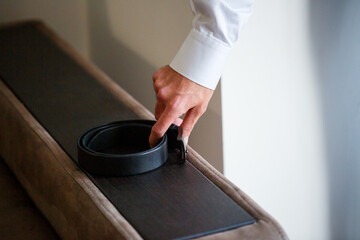A Stylish Hand is Delicately Placing a Luxurious Belt on a Soft, Comfortable Couch