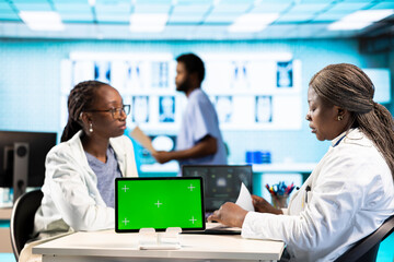 African american medic and patient discuss recovery plan next to green screen, meeting during checkup visit. Specialist consulting young girl to ensure wellness, health care practice.