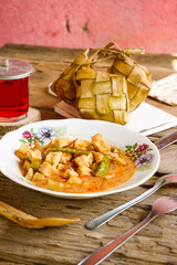 Vertical Photo of menu Lebaran ketupat, lontong and vegetable soup tofu rambak, potatoes with red syrup drink. Ketupat is a typical dish during Eid al-Fitr in Indonesia