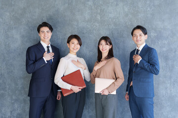 胸に手を当てるカメラ目線のビジネスマン男女複数人