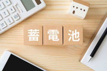 蓄電池と書かれたブロック、ミニチュアの家、電卓