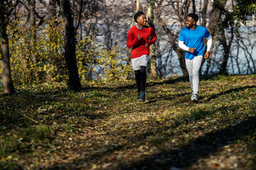 Fototapeta premium Two black runner friends running in nature towards camera on fitness day.