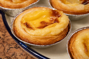 Portugal's traditional sweet dessert Pastel de nata egg custard tart pastry in cup close up on wooden background