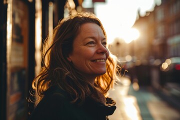 Portrait of smiling middle-aged woman in the city at sunset