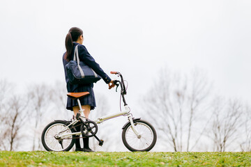 自転車通学する制服姿の中学生・高校生の女の子
