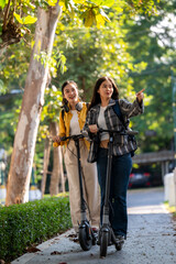 Obraz premium Two women riding scooters on a sidewalk