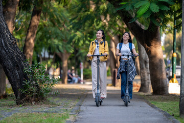 Obraz premium Two women riding scooters down a path