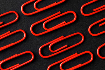 Red paper clips on black background, flat lay