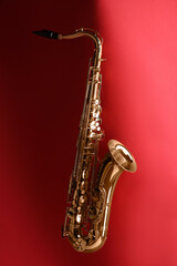 Jazz. One golden saxophone on red background
