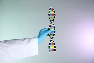 Scientist with DNA structure model on color background, closeup