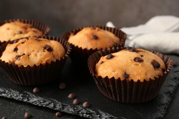 Delicious muffin with chocolate chips on black table, closeup