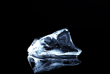 Naklejka premium Piece of clear ice on black mirror surface