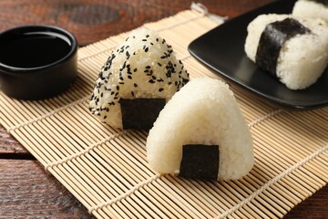 Rice balls (onigiri) and soy sauce on wooden table, closeup. Traditional Japanese dish