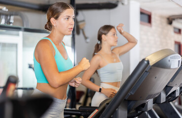 Fototapeta premium Girl in sportswear are running on treadmill. Physical activity, healthy lifestyle. Easy and simple weight loss, affordable workouts, active self-care in crossfit gym