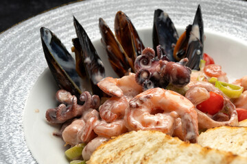 Seafood cocktail on a plate with sauce, vegetables, and toasted bread
