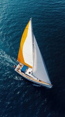Fototapeta premium Aerial View of White Sailboat with Yellow Stripes Gliding Across Deep Blue Ocean with Foam Wake