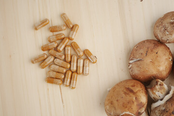 Dietary supplements beside natural mushrooms on wooden surface © Towfiqu Barbhuiya 