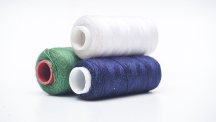 Pile of white, blue navy, and green spool of sewing thread isolated on white background