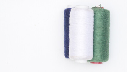 Pile of green, blue navy, and white spool of sewing thread isolated on white background