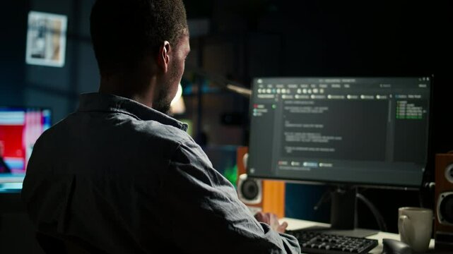 Black man programmer manages code and scripts in artificial intelligence and machine learning on dual monitors computer setup. Male freelancer uses pc to guarantee cyber security. Camera A.