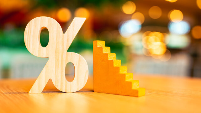Percent symbol placed on table with steps of a ladder. Concept of increasing and decreasing interest step by step.