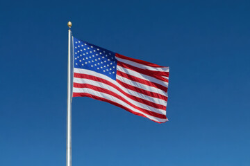 Obraz premium American flag flies in the wind, draped over a historic building, under a clear blue sky.