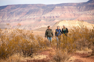 Three adult women hiking together in a desert landscape on a warm winter day. Enjoying the sun and the great outdoors while exercising and staying active