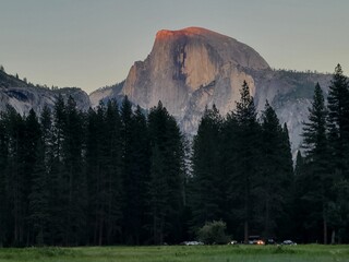 The golden rays of the setting sun shine on the very edge of Half Dome at sunset