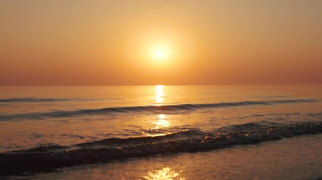 4K Slow motion shot of a beautiful sunset at Mandvi Beach in Kutch, Gujarat, India. Sea waves and entire sea becomes golden in colour during the sunset. Orange colored sea. Natural sea background.