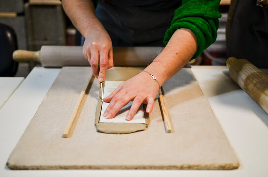 Potter cutting clay slab with precision in workshop